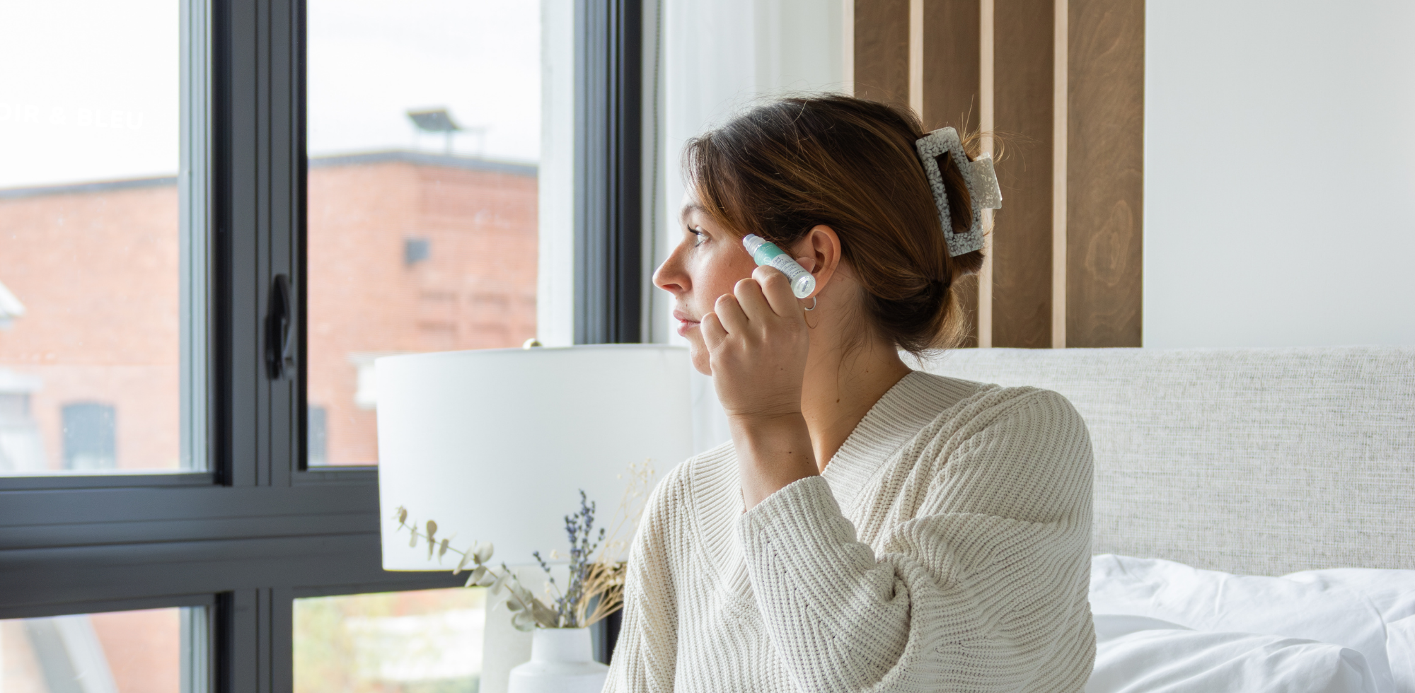 Femme qui s’applique un mélange d’huiles essentielles Bleu Lavande sur la tempe