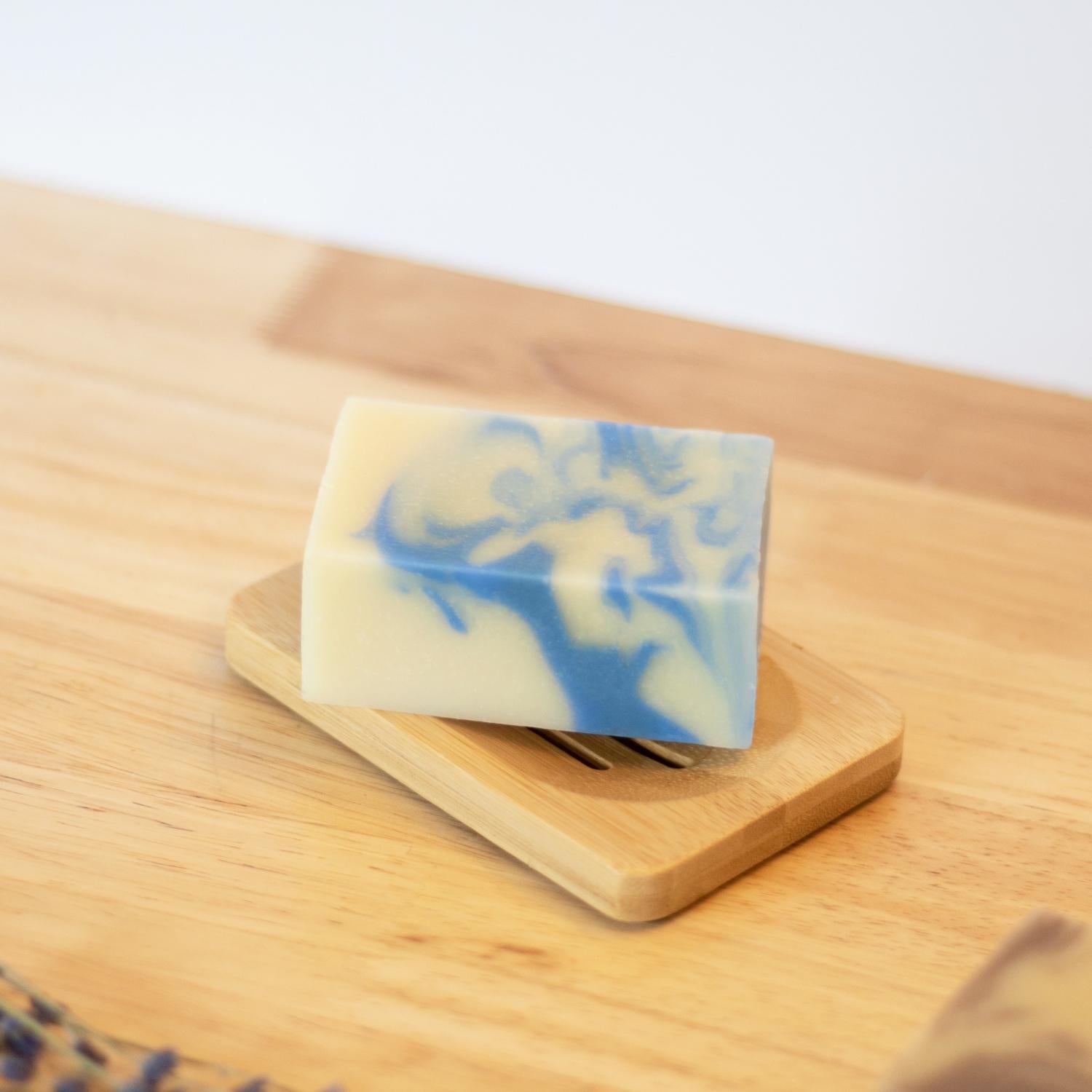 Savon en barre à la lavande sur un porte-savon en bambou sur une table de bois avec des brins de lavande